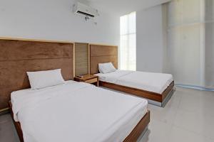1 Schlafzimmer mit 2 Betten und einem Fenster in der Unterkunft Capital O 92604 Hotel Uin Syariah Near Kampus UIN Mataram in Mataram