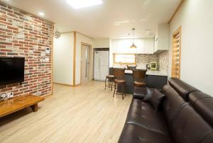 a living room with a leather couch and a brick wall at Arche House B in Jeju