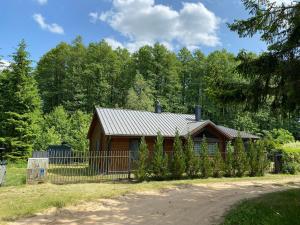 Cabaña de madera pequeña con valla y árboles en Pietraszówka, en Piertanie