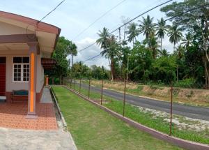 une maison avec une clôture à côté d'une route dans l'établissement Adilah Homestay A, à Pasir Puteh