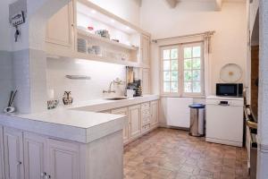 una cucina con armadi bianchi, lavandino e finestra di VILLA BELLA AVEC SA MAGNIFIQUE PISCINE a Marsilly