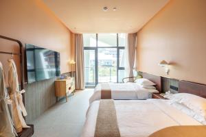 um quarto de hotel com duas camas e uma televisão em YAN YU JIAN Art Hotel em Zhangjiajie