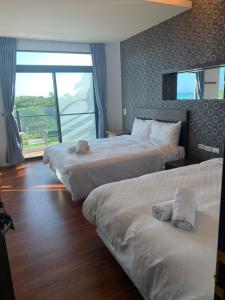 a hotel room with two beds and a large window at Happiness Inn in Kenting