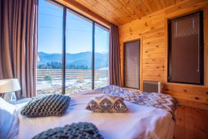 a bedroom with a bed with a large window at Svaneti Сountryside 1 in Shkaleri