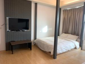 a bedroom with a bed and a flat screen tv at Happiness Inn in Kenting