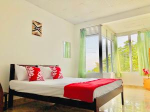 Un dormitorio con una cama con almohadas rojas y una ventana en Blossom Rest, en Kandy