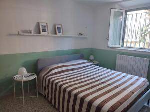 a bedroom with a bed with a striped blanket and a window at Casa Venezia in Senigallia