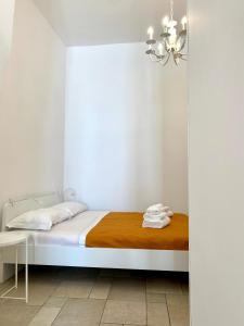 una camera bianca con un letto e un lampadario a braccio di Dimora Zia Giovanna - Puglia Mia Apartments a Monopoli