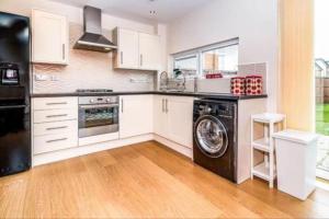 a kitchen with a washer and dryer in it at Nice house + Car parking + Close to the city centre in Manchester