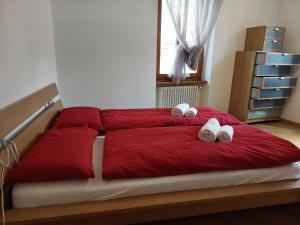 1 dormitorio con 1 cama roja y 2 toallas en Appartamento Borgo Centro, en Borgo