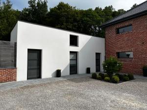 ein weißes Haus mit schwarzen Fenstern und einem Backsteingebäude in der Unterkunft Studio - Le Clos du fond cailloux in Longuenesse