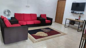 un soggiorno con divano rosso e tavolo di Teratak Malaika a Huma