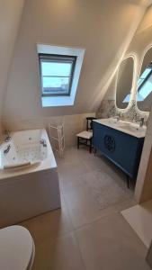 a bathroom with two sinks and a toilet and two mirrors at Villa 5*, mer à 3 mn, piscine intérieure à 28° in Gonneville-en-Auge