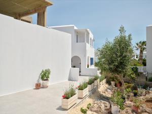 a white house with potted plants on the side of it at Bedspot Apartments Paros in Naousa