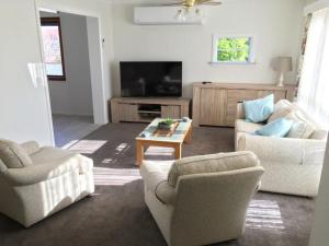 a living room with two chairs and a television at Eagles Nest - Ardrossan in Ardrossan