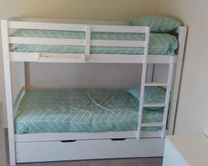 two bunk beds in a room with green sheets at Eagles Nest - Ardrossan in Ardrossan