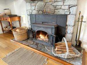 a stone fireplace in a living room with a fire place at White Shell Cottage - Woodfire & Beachfront in Falmouth