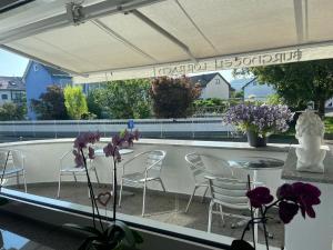 een patio met stoelen en een tafel met paarse bloemen bij Burghotel Lörrach in Lörrach