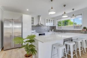 eine weiße Küche mit einer großen weißen Theke und Stühlen in der Unterkunft Stylish family home, centrally located. in Thirlmere