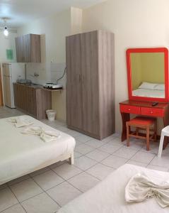 a bedroom with two beds and a red dresser and a mirror at Rooms Anastasia Paralia in Katerini