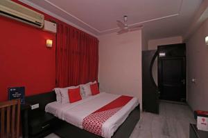 1 dormitorio con 1 cama con pared roja en OYO Flagship 80902 Swagat Hotel en Bhiwadi