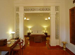 Dormitorio con cama, escritorio y sidx sidx sidx sidx en Visalam Chettinad Palace - CGH Earth en Chettinadu