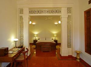 - une chambre avec un lit et un bureau dans l'établissement Visalam Chettinad Palace - CGH Earth, à Chettinadu