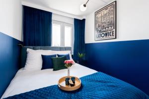 a blue bedroom with a bed with a blue wall at Kairos Apartments - Gwarek - darmowy parking, ścisłe centrum in Katowice