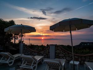 a group of chairs and umbrellas in front of a sunset at Casa Astra in Anacapri