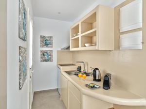 a small kitchen with white cabinets and a sink at Bedspot Apartments Paros in Naousa