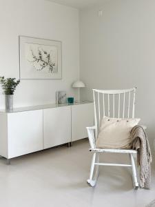 a white room with a chair and a desk at Cozy apartment with free parking in Espoo