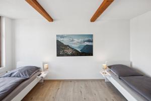 2 camas en un dormitorio con paredes blancas y suelo de madera en FENUS Apartment mit traumhaftem Bergblick, en Grabs