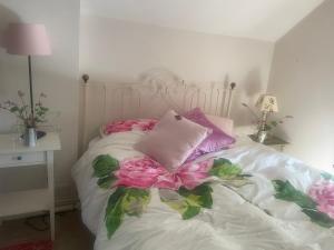 ein weißes Bett mit rosa Blumen drauf in der Unterkunft Bradford Mill in Tiverton