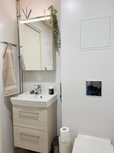 a white bathroom with a sink and a mirror at Cozy apartment with free parking in Espoo