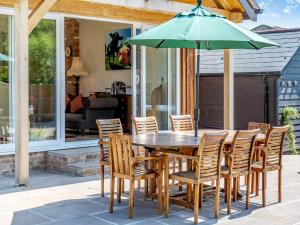 - une table en bois avec des chaises et un parasol sur la terrasse dans l'établissement The Farmhouse, à Ferndown