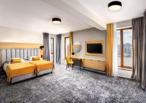 sypialnia z łóżkiem, biurkiem i telewizorem w obiekcie Hotel Akvamarín w Beszeniowej