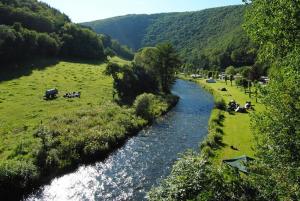 Un río en un campo con gente sentada en la hierba en Chalet Teifëlslee en Goebelsmuhle