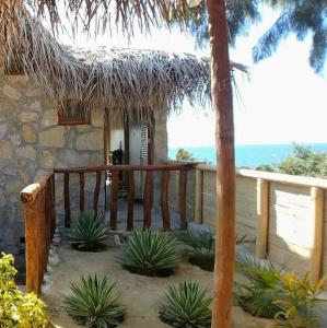 Marcilia Beach Bungalows في لوس أورغانوس: شرفة منزل مع مجموعة من النباتات