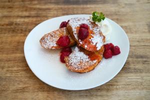 a plate of food with strawberries and powdered sugar at Kokotel Bangkok Surawong in Bangkok