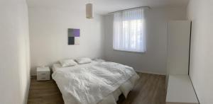 a white bedroom with a bed and a window at Casa a Suglegl in Savognin