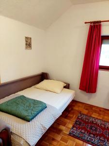 a small bedroom with a bed with a red curtain at Holiday Home Mirza in Sarajevo