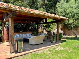 een houten pergola met stoelen en tafels in een tuin bij Villa a Cala Piccola in Monte Argentario