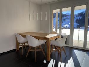 comedor con mesa de madera y sillas blancas en Casa a Suglegl en Savognin