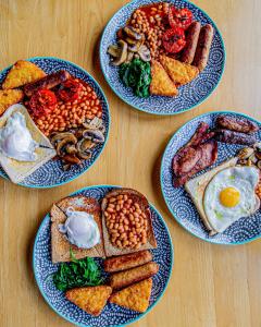 four plates of breakfast foods on a wooden table at Wayfarers Lodge in Penzance