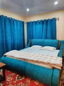 a bedroom with a blue bed with blue curtains at Home Sweet Home in Srinagar