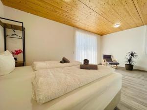 a bedroom with two white beds and a wooden ceiling at GrenzApartments in Bietingen