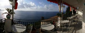 a balcony with tables and chairs and the ocean at Hotel La Perla in Praiano