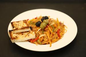 a white plate of food with pasta and vegetables at Hotel Udika Palace in Kaohni