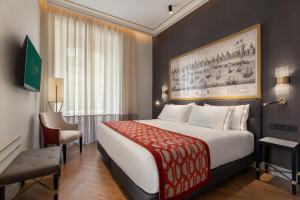 a hotel room with a large bed and a chair at Áurea Casa Palacio Sagasta by Eurostars Hotel Company in Cádiz