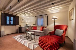 a living room with a red chair and a couch at Áurea Casa Palacio Sagasta by Eurostars Hotel Company in Cádiz